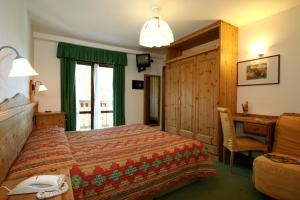 ピーラにあるHotel Chalet des Alpesのベッド、デスク、窓が備わるホテルルームです。