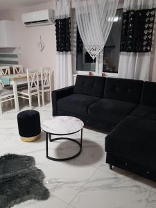 a living room with a black couch and a table at Domki Prowansalskie in Mysłakowice
