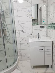 a white bathroom with a sink and a shower at Domki Prowansalskie in Mysłakowice