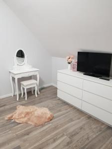 a living room with a tv and a table and a desk at Domki Prowansalskie in Mysłakowice