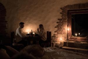 a man and woman sitting at a table in a dark room at Domek Hobbita z jaskinią SPA - Osada Jaworzyny in Tokarnia