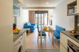 cocina y sala de estar con mesa y sillas azules en Tgna Rambla 68, en Tarragona
