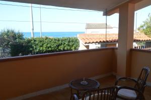 balcón con mesa, sillas y vistas al océano en Casa della Salsedine, en S'Archittu