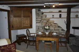 comedor con mesa, sillas y pared de piedra en The Hideaway, en Alston