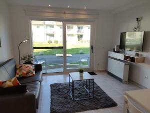 een woonkamer met een bank en een tv bij Appartement Biaritz in Bredene