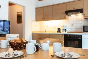 a table with plates and mugs and a basket of bread at Biobauernhof Stegerbauer in Maria Alm am Steinernen Meer