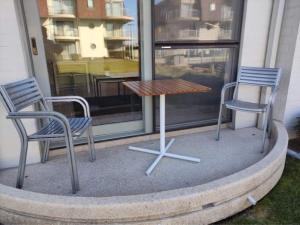 twee stoelen en een tafel en twee stoelen voor een raam bij Appartement Biaritz in Bredene