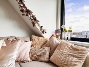 ein Sofa mit Kissen in einem Zimmer mit Fenster in der Unterkunft Catharine Suite in Breda