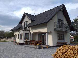 a white house with a black roof and a patio at Kapitański Dworek in Krynica Morska
