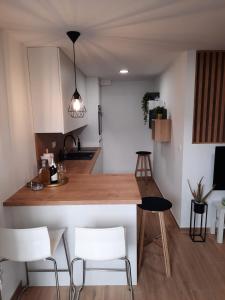 une cuisine avec un comptoir en bois et des chaises blanches dans l'établissement Anita, à Zaostrog
