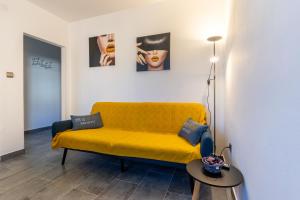 a yellow couch in a living room with a table at Apartment Brđanović in Cres