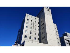 Central Hotel Toride - Vacation STAY 09920v في Toride: مبنى أبيض طويل وخلفه سماء زرقاء
