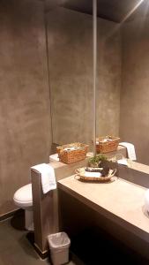 a bathroom with a toilet and a sink with baskets on the counter at Hoteles Pueblo de Tierra in San Pedro de Atacama