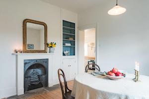 a dining room with a table with a mirror and a fireplace at West Cottage by Bloom Stays in Dungeness