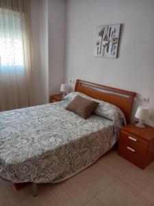 a bedroom with a bed and a night stand and a window at Práctico apartamento en el Centro de Marina D´or in Oropesa del Mar