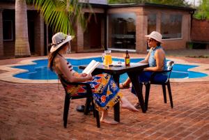 zwei Frauen an einem Tisch vor einem Pool in der Unterkunft Posada Yvoty in Puerto Iguazú