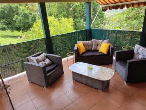 a screened in porch with chairs and a coffee table at Appartement Kelysa in Le Marin