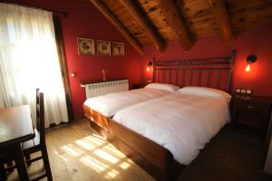 a bedroom with a large bed with red walls at Hotel Rural El Mirador de los Pirineos in Santa Cruz de la Serós