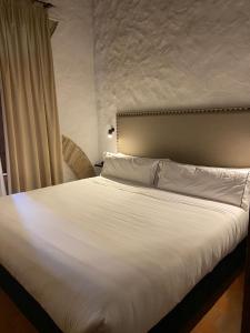 a hotel room with a white bedspread and white comforter at Tugasa Hotel Convento San Francisco in Vejer de la Frontera