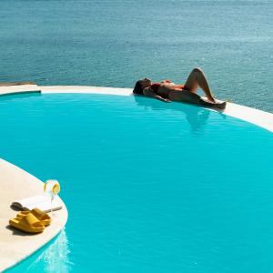 a woman laying on a surfboard in a swimming pool at Insólito Boutique Hotel & Spa in Búzios