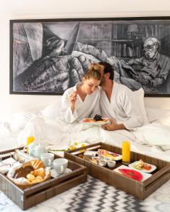 a bride and groom eating breakfast in bed at Insólito Boutique Hotel & Spa in Búzios