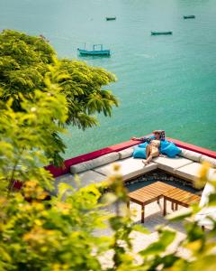 une femme assise sur un canapé à côté de l'eau dans l'établissement Insólito Boutique Hotel & Spa, à Búzios