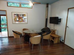 a dining room with a table and chairs and a tv at Sweetwater Cottage. A private mountain escape in Upper Burringbar