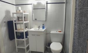 a white bathroom with a toilet and a sink at Aguazul 120 in Tías +3 photos