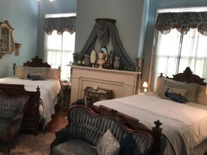 a bedroom with two beds and a chair and windows at Shadowlawn Bed and Breakfast in Columbus