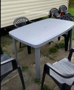 a white table with two chairs and a bench at Caravan Primrose Valley WW in Hunmanby