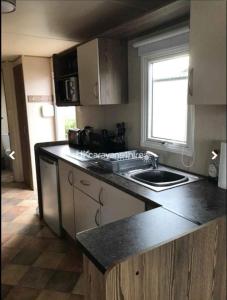 a kitchen with a counter and a sink and a window at Caravan Primrose Valley WW in Hunmanby