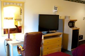 a room with a desk with a television on a dresser at Lamplighter Inn & Suites in San Luis Obispo