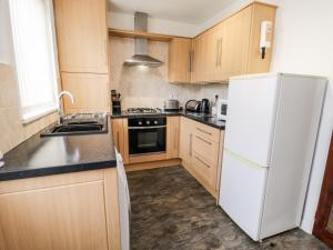 a kitchen with wooden cabinets and a white refrigerator at Yeoman Terrace in Marske-by-the-Sea