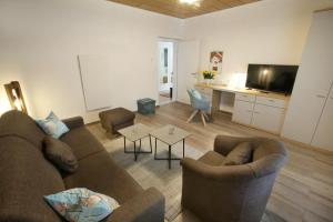 sala de estar con sofá, sillas y TV de pantalla plana en Haus Josef, en Sankt Andrä bei Frauenkirchen