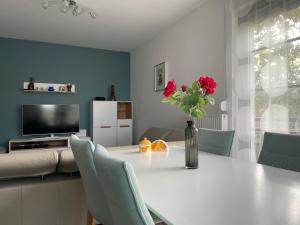 a white table with a vase of flowers on it at D-S Apartman Stella in Zamárdi