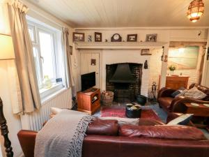 a living room with a leather couch and a fireplace at Inglenook Cottage in Whitby