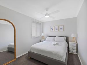 - une chambre blanche avec un lit et un miroir dans l'établissement Beached At Blue Bay, à Blue Bay 