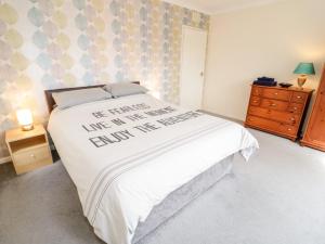 a bedroom with a bed with white sheets and a dresser at Treetops in Colwyn Bay