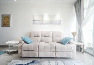 un sofá blanco en una sala de estar blanca con almohadas azules en zara1881 muslim homestay@putrajaya en Putrajaya
