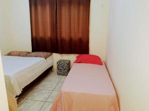 a small room with two beds and a window at Casa amarela 02 jdm moema in Londrina