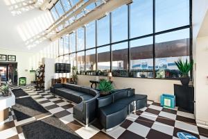 a lobby with black leather furniture and large windows at The Atrium Resort by VSA Resorts in Virginia Beach