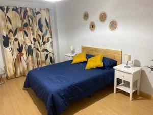 - une chambre avec un lit bleu et des oreillers jaunes dans l'établissement El Refugio de Yetana Centro ciudad con parking, à Carthagène