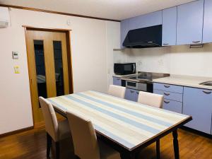 a kitchen with a table and chairs in a room at 佐渡民宿 憩 IKOI GUEST HOUSE & Cafe Bar in Sado