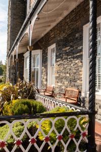 ein Steinhaus mit zwei Bänken auf der Veranda in der Unterkunft Windermere Hotel in Windermere