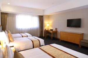 a hotel room with two beds and a flat screen tv at Fushin Hotel - Tainan in Tainan