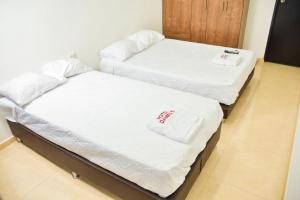 two beds in a room with white sheets and towels at Hotel Daniels in Fonseca