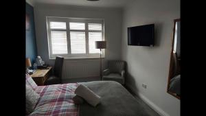 1 dormitorio con cama, escritorio y ventana en Room in Guest room - Apple House Wembley en Edgware