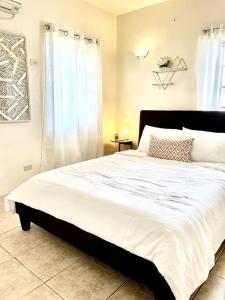 タムニンにあるbeautiful 4 bedroom tumon houseのベッドルーム1室(白いシーツが敷かれた大型ベッド1台、窓付)
