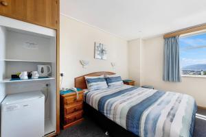 a small bedroom with a bed and a window at Marquis Hotel Motel in Hobart