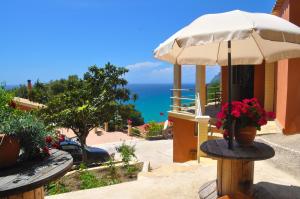 a patio with an umbrella and a view of the ocean at Villa Takis on Pelekas beach Small house with garden and sea view in Pelekas
